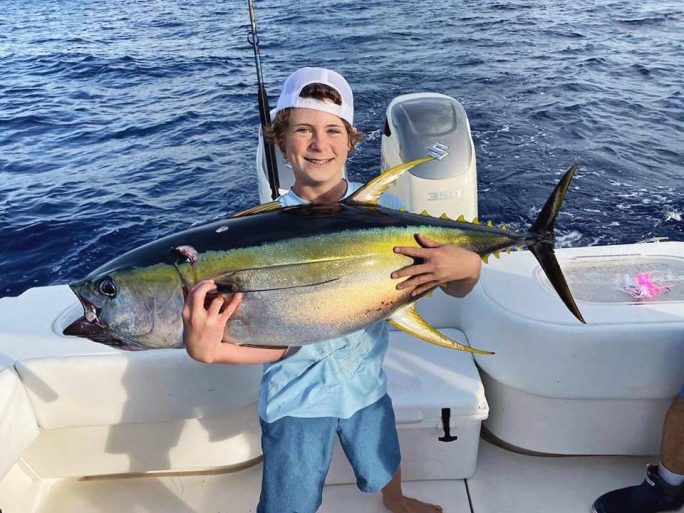 Boy Holding a Yellow Fin Fish on Boat